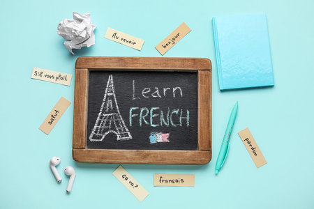 Chalkboard with text LEARN FRENCH, stationery and earphones on blue backgroundの写真素材