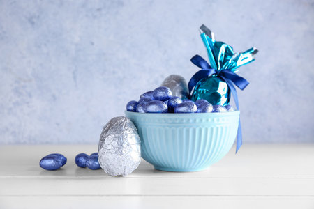 Bowl of chocolate Easter eggs on light wooden tableの写真素材