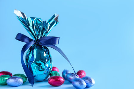 Sweet chocolate Easter eggs wrapped in foil on color backgroundの写真素材