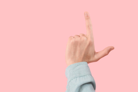 Hand of man showing loser gesture on pink backgroundの写真素材