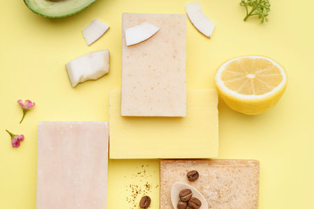 Composition with soap bars and natural ingredients on yellow background