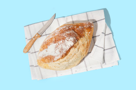 Fresh loaf of bread and knife on blue backgroundの写真素材