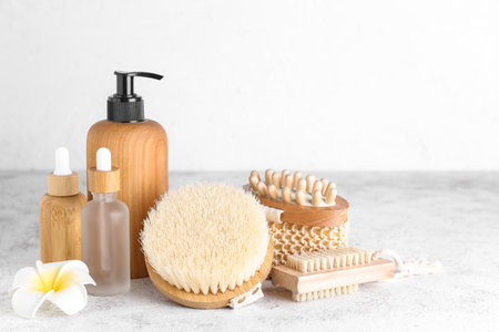 Different massage brushes, sponge and bottles of cosmetic products on light backgroundの写真素材