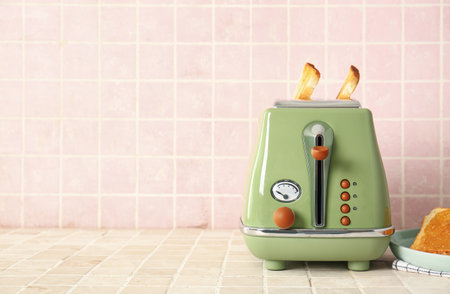 Modern toaster with crispy bread slices on tile tableの写真素材