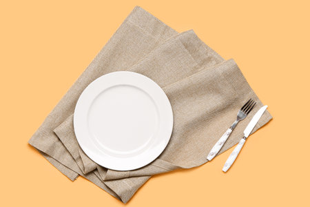 Table setting with clean napkin on orange backgroundの写真素材