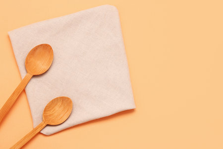 Wooden spoons and folded napkin on color backgroundの写真素材