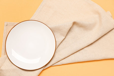 Empty plate and clean napkin on color backgroundの写真素材