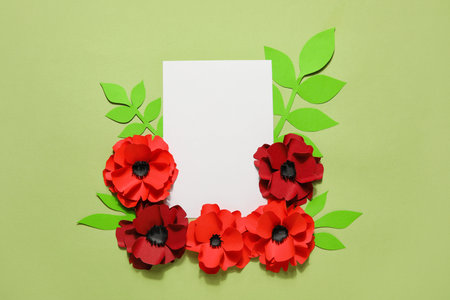 Blank paper sheet with poppy flowers and leaves on green background