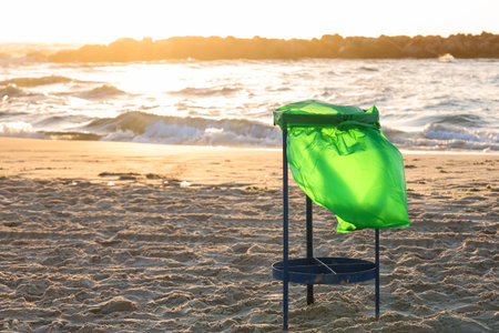 Garbage container on sand near sea at sunsetの写真素材