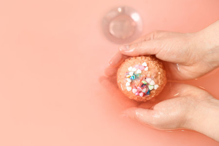 Woman putting bath bomb into water in room, closeup