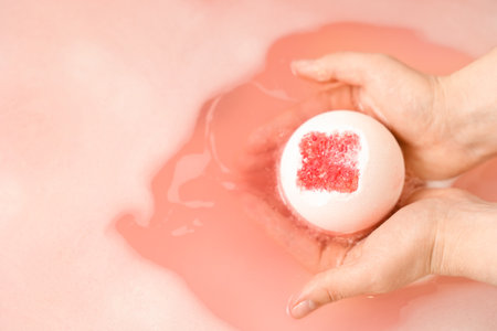 Woman putting bath bomb into water in room, closeupの写真素材