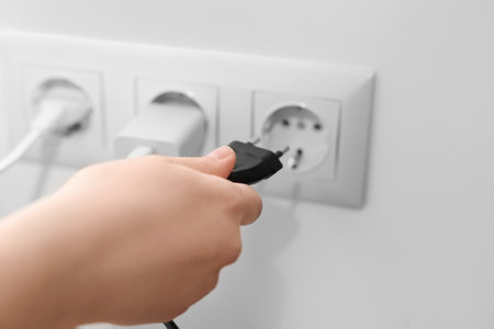 Woman putting plug into socket at home, closeupの写真素材