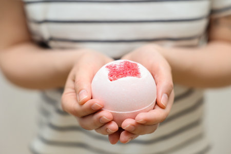 Woman with bath bomb on light background, closeupの写真素材