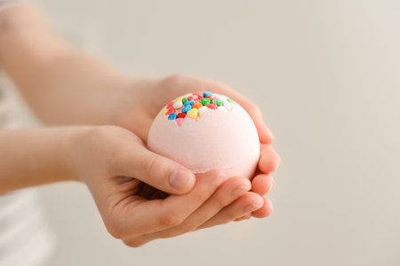 Woman with bath bomb on light background, closeupの写真素材