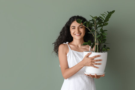 Beautiful young woman with houseplant on color backgroundの写真素材