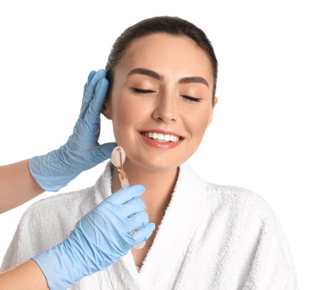 Young woman receiving facial massage on white background