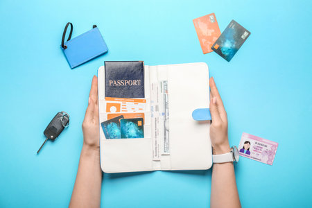Female hands with travel organizer and different things on color backgroundの写真素材