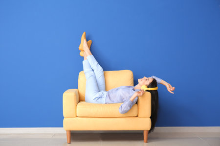 Young woman relaxing in armchair near color wallの写真素材