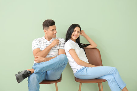Young couple relaxing on chairs near color wallの写真素材