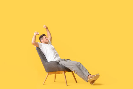 Young man relaxing in armchair against color backgroundの写真素材