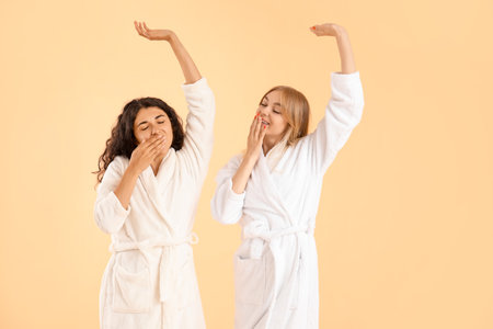 Beautiful young women in bathrobes on color backgroundの写真素材