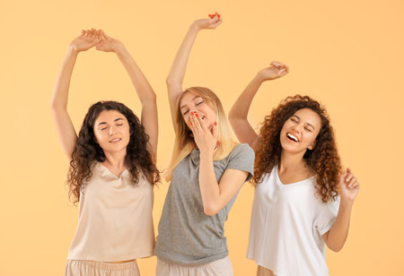 Beautiful young women in pajamas on color backgroundの写真素材