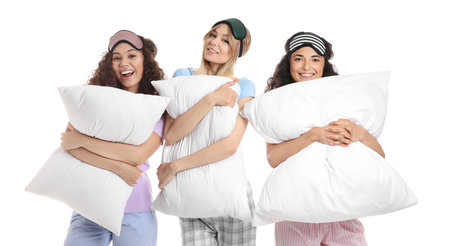 Beautiful young women in pajamas and with pillows on white backgroundの写真素材