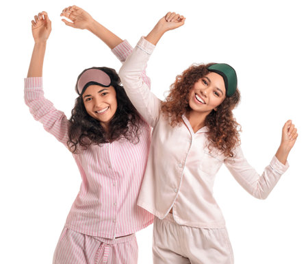 Beautiful young women in pajamas and with sleep masks on white backgroundの写真素材