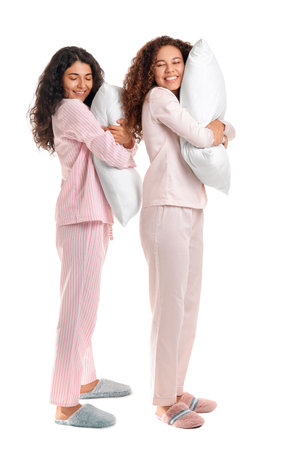 Beautiful young women in pajamas and with pillows on white backgroundの写真素材
