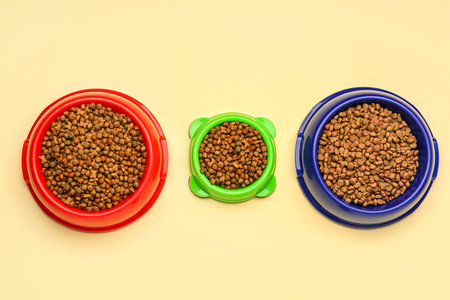 Different bowls with dry pet food on color backgroundの写真素材