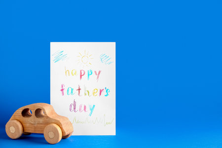 Greeting card for Father's Day and wooden car on blue backgroundの写真素材