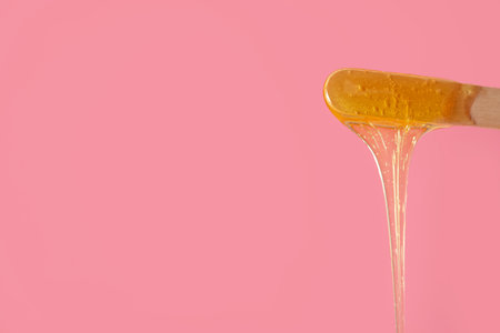 Spatula with sugaring paste on pink background, closeupの写真素材