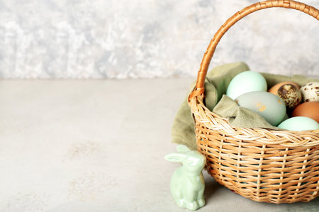 Basket with Easter eggs and bunny on table near grunge wallの写真素材