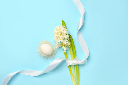 Beautiful hyacinth flower, Easter egg and ribbon on blue backgroundの写真素材