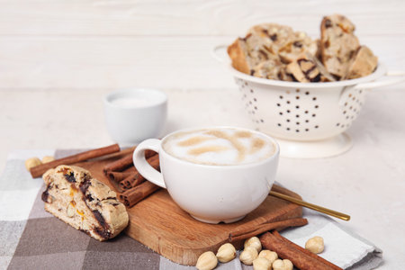 Board with delicious biscotti cookies, hazelnuts and cup of coffee on napkinの写真素材