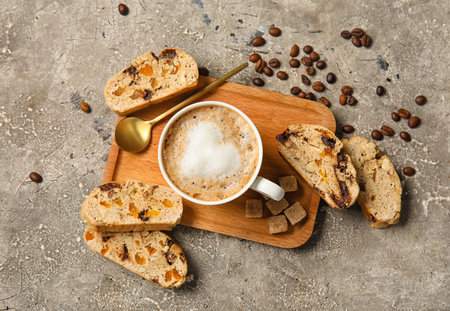 Board with delicious biscotti cookies and cup of coffee on gray grunge backgroundの写真素材