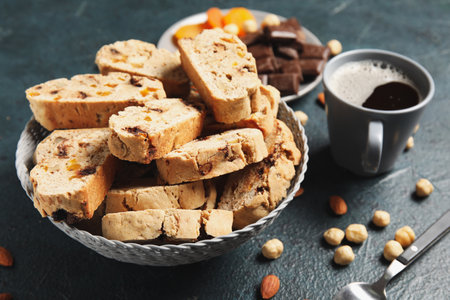 Delicious biscotti cookies, nuts, cup of coffee and chocolate on grunge backgroundの写真素材