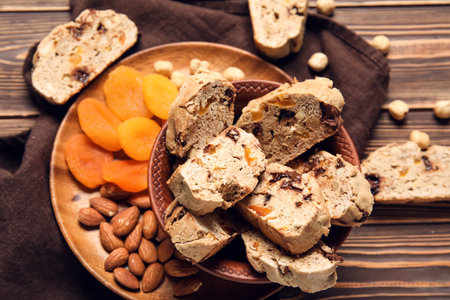 Board with delicious biscotti cookies, dried apricots and nuts on brown wooden backgroundの写真素材