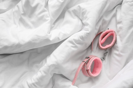 Pink handcuffs from sex shop on white blanketの写真素材
