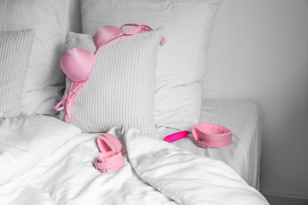 Bed with bra, vibrator, collar and handcuffs from sex shop in the morningの写真素材