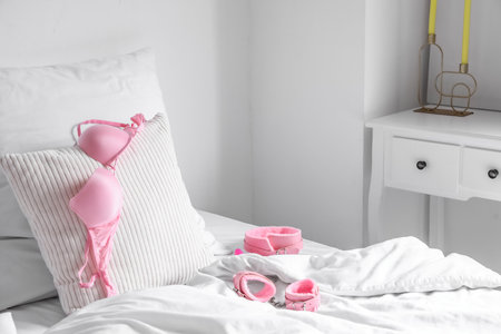 Bed with bra, collar and handcuffs from sex shop in the morningの写真素材