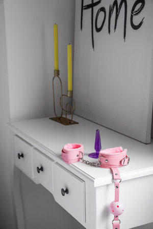 Handcuffs and anal plug on table in bedroomの写真素材
