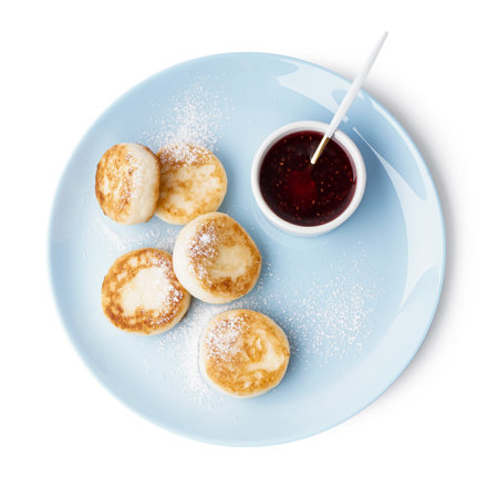 Plate with tasty cottage cheese pancakes and strawberry jam on white backgroundの写真素材