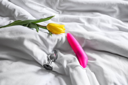 Vibrator, anal plug and tulip on bed in the morning, closeupの写真素材