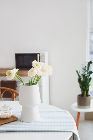 Vase with ranunculus flowers on dining table in kitchenの写真素材