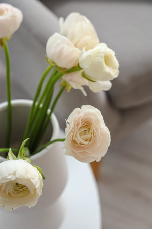 Vase with ranunculus flowers on table in living room, closeup