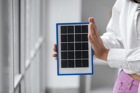 Teenage girl with portable solar panel at home, closeup