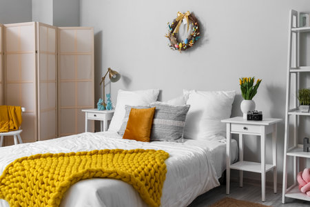 Interior of light bedroom with Easter wreath and tulips in vaseの写真素材