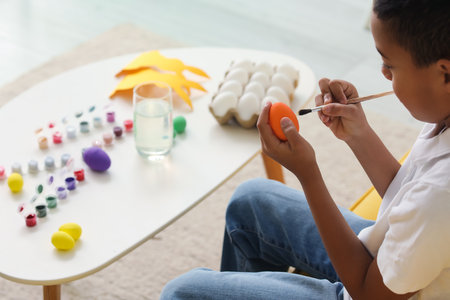 Little African-American boy painting Easter egg at homeの写真素材