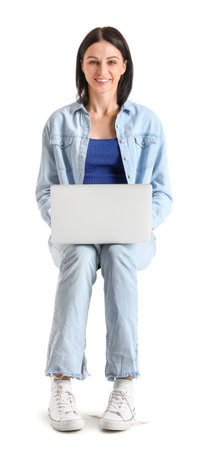 Pretty young woman with laptop sitting on chair against white backgroundの写真素材